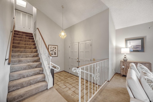 stairs with high vaulted ceiling, a textured ceiling, and carpet flooring