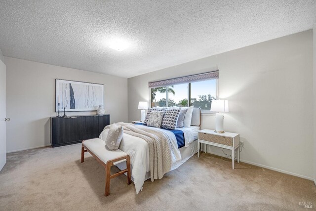 bedroom featuring light carpet and a textured ceiling