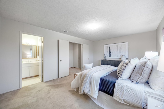 bedroom featuring ensuite bath, sink, light carpet, and a textured ceiling