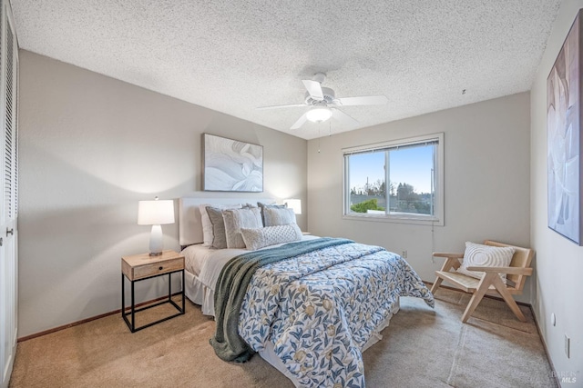 bedroom with ceiling fan, light carpet, and a textured ceiling