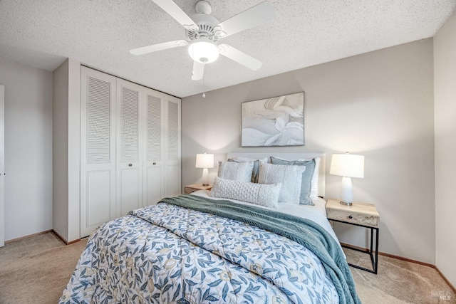 bedroom with ceiling fan, a closet, light carpet, and a textured ceiling