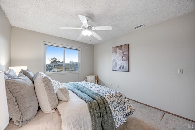 bedroom featuring ceiling fan, light carpet, and a textured ceiling