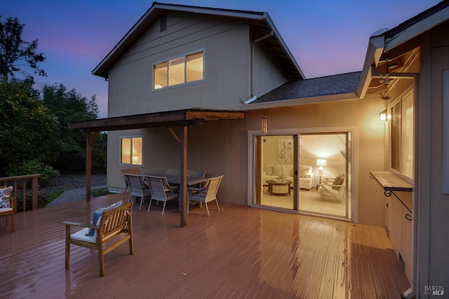 back house at dusk featuring a deck