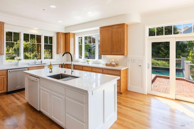 kitchen featuring white cabinets, dishwasher, sink, and an island with sink