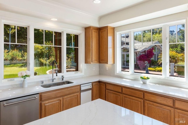 kitchen featuring sink, light stone counters, crown molding, stainless steel dishwasher, and backsplash