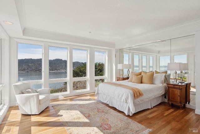 bedroom with a water view and wood finished floors