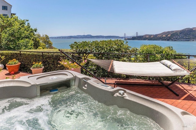 balcony featuring a hot tub and a water and mountain view