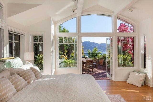 bedroom with access to exterior, a mountain view, vaulted ceiling, and hardwood / wood-style floors