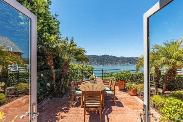 view of patio / terrace featuring a water and mountain view and outdoor dining space