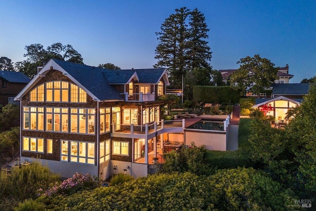 back house at dusk featuring a balcony