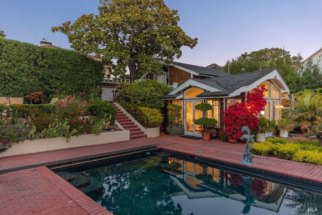 pool at dusk featuring a patio