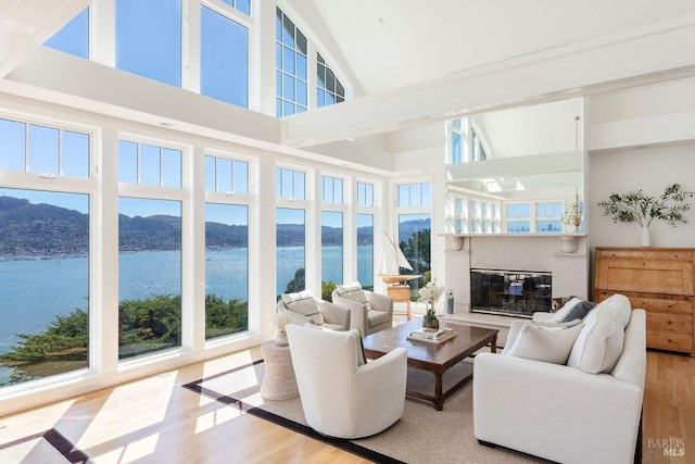 living room with a high ceiling, a water and mountain view, and light hardwood / wood-style floors