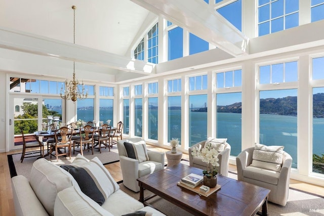 sunroom featuring a chandelier, vaulted ceiling, and a water view