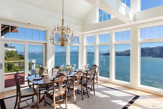 sunroom with a water view, an inviting chandelier, and vaulted ceiling