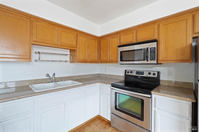 kitchen with appliances with stainless steel finishes, sink, and white cabinets