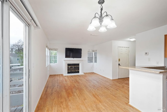 unfurnished living room featuring a chandelier and light hardwood / wood-style floors