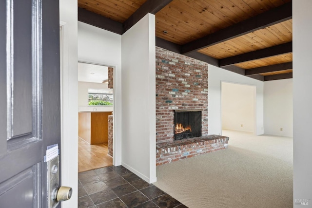 unfurnished living room featuring wood ceiling, a fireplace, beamed ceiling, and dark colored carpet