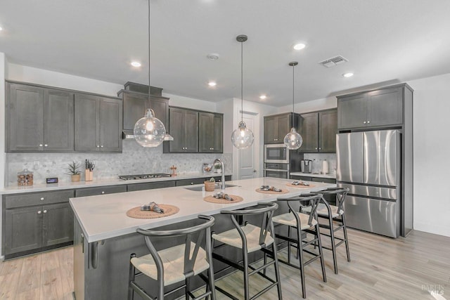 kitchen featuring hanging light fixtures, a center island with sink, and appliances with stainless steel finishes