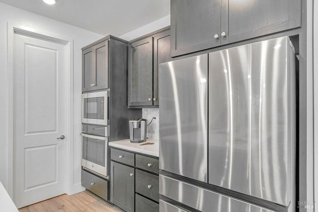 kitchen featuring stainless steel appliances, dark brown cabinetry, and light wood-type flooring