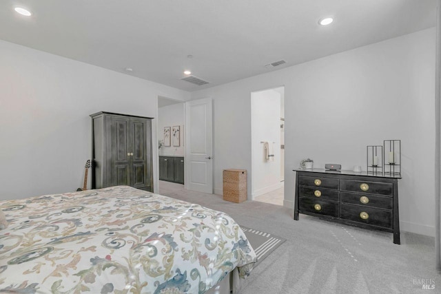 bedroom featuring ensuite bathroom and light carpet