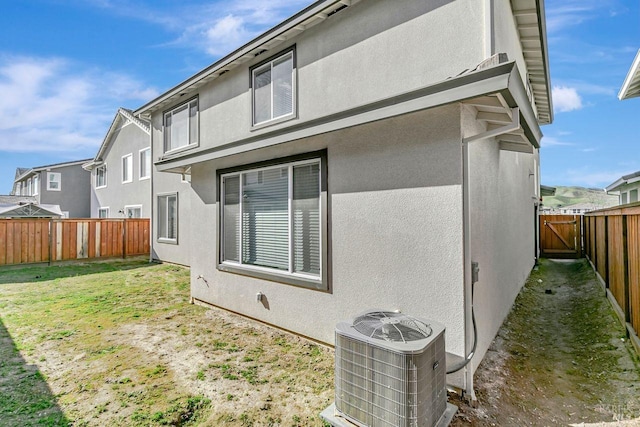 back of house with central AC unit and a lawn