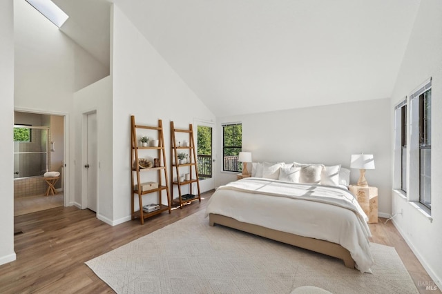 bedroom with hardwood / wood-style floors, a skylight, and high vaulted ceiling