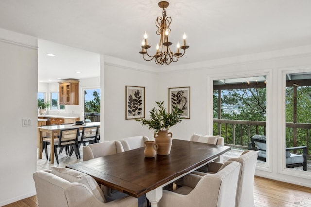 dining room with an inviting chandelier, a healthy amount of sunlight, sink, and light hardwood / wood-style flooring