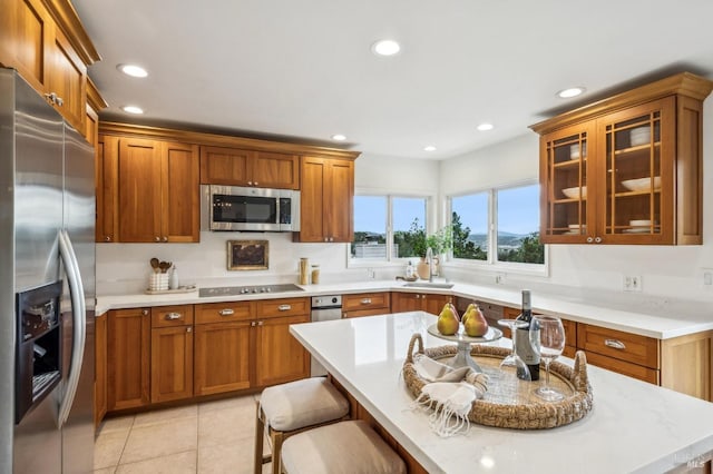 kitchen featuring light tile patterned flooring, appliances with stainless steel finishes, sink, and a kitchen bar