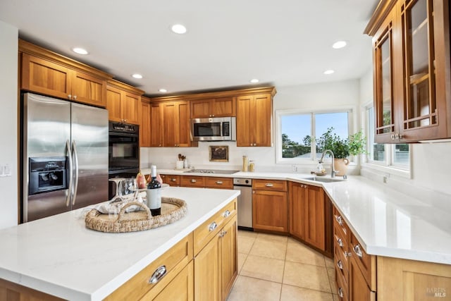 kitchen with sink, light tile patterned floors, appliances with stainless steel finishes, a center island, and light stone counters