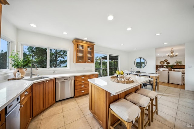 kitchen with sink, a kitchen breakfast bar, a center island, stainless steel dishwasher, and light tile patterned floors