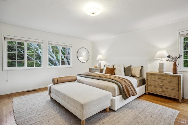 bedroom with multiple windows, hardwood / wood-style floors, and ornamental molding