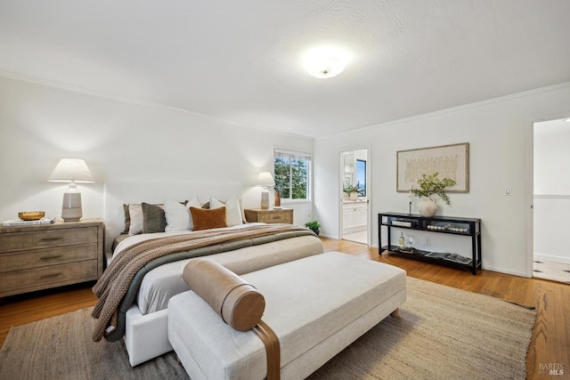 bedroom with crown molding, ensuite bath, and wood-type flooring