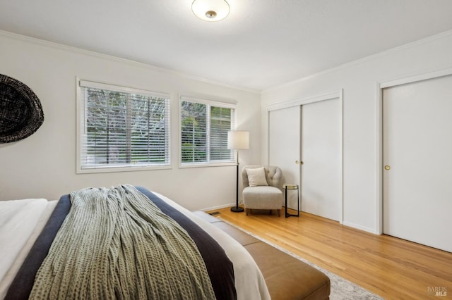 bedroom featuring crown molding, hardwood / wood-style flooring, and multiple closets