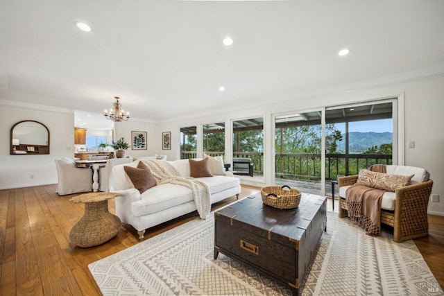 living room with a notable chandelier, ornamental molding, and light hardwood / wood-style floors