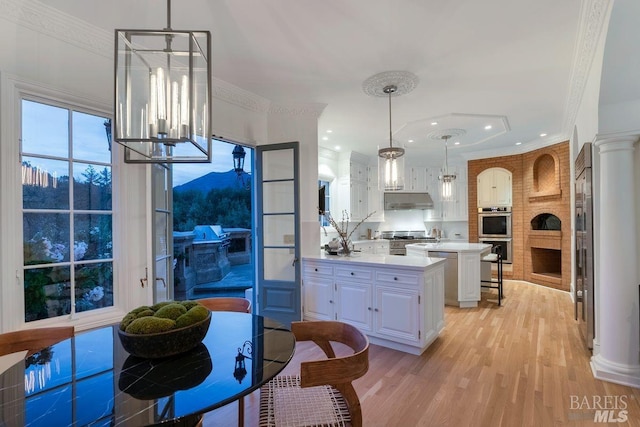 kitchen with white cabinetry, hanging light fixtures, and a breakfast bar area