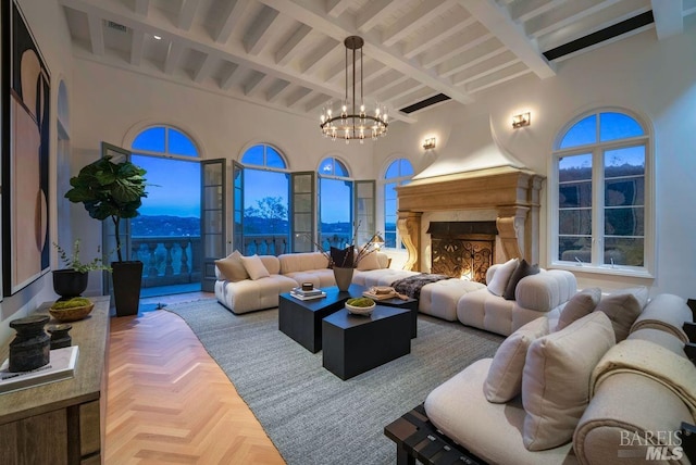 living room featuring parquet flooring, beam ceiling, a notable chandelier, a fireplace, and a high ceiling