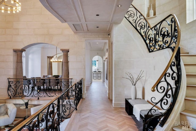 hall with light parquet flooring, coffered ceiling, and tile walls