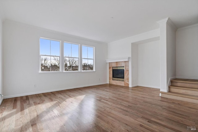 unfurnished living room with a tiled fireplace, hardwood / wood-style flooring, and ornamental molding