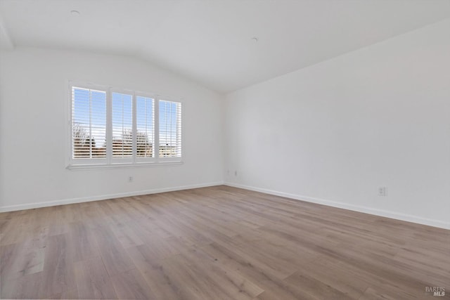 unfurnished room featuring lofted ceiling and light wood-type flooring