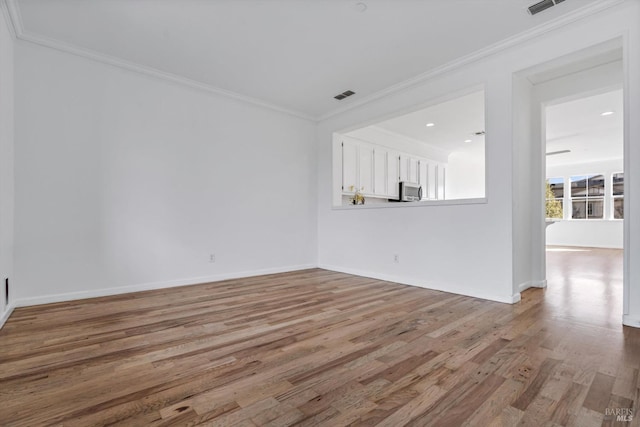 spare room featuring crown molding and light hardwood / wood-style flooring