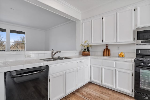 kitchen featuring sink, white cabinetry, black appliances, ornamental molding, and tile countertops