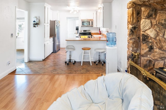 kitchen with sink, a breakfast bar area, white cabinets, kitchen peninsula, and stainless steel appliances