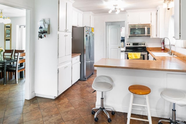 kitchen featuring white cabinetry, sink, a kitchen breakfast bar, kitchen peninsula, and stainless steel appliances