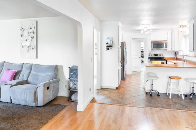 kitchen with sink, a breakfast bar, appliances with stainless steel finishes, white cabinetry, and kitchen peninsula