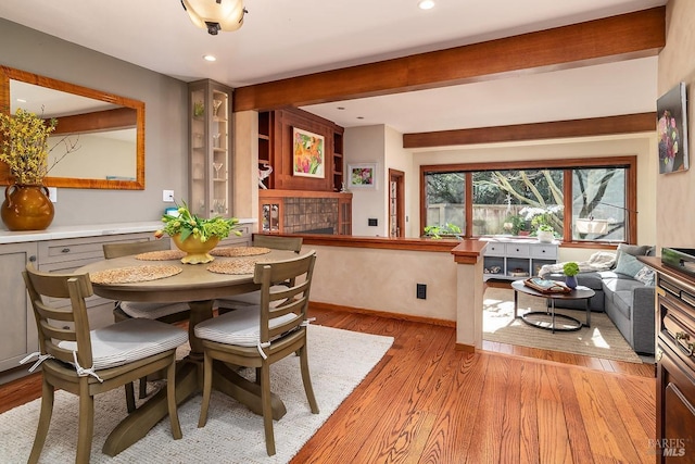 dining room featuring light wood-style flooring, baseboards, beamed ceiling, and recessed lighting