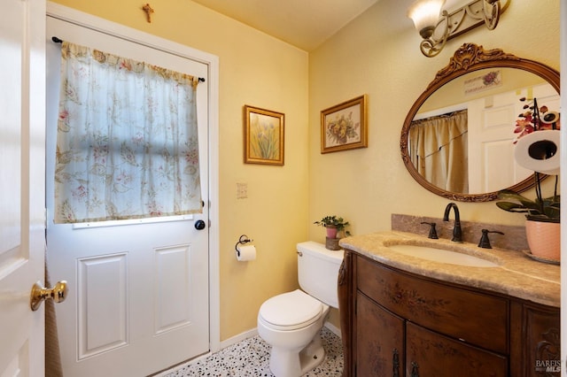 bathroom featuring toilet, vanity, and baseboards