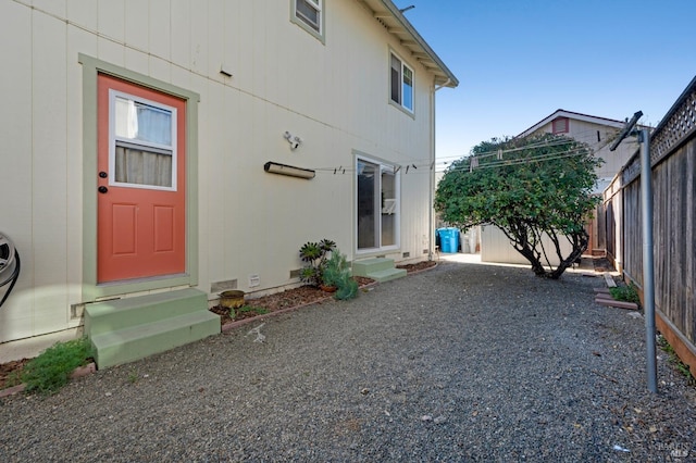 view of exterior entry featuring gravel driveway and fence