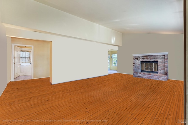 unfurnished living room with vaulted ceiling, a brick fireplace, and hardwood / wood-style flooring