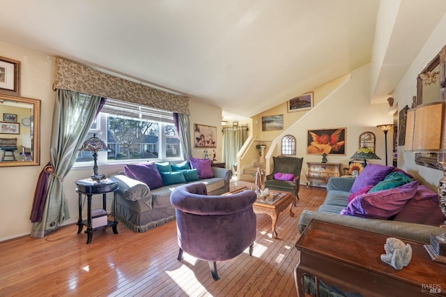 living room featuring vaulted ceiling, stairway, and light wood finished floors