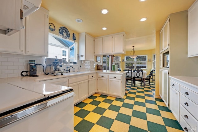 kitchen featuring light countertops, backsplash, a sink, and white cabinetry